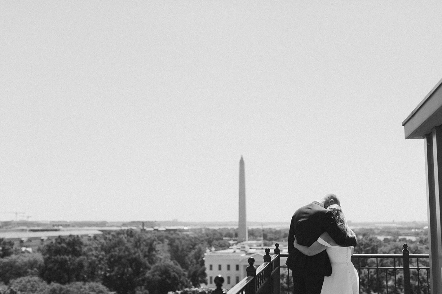 Bride and groom hugging with Washington Monument in the background.