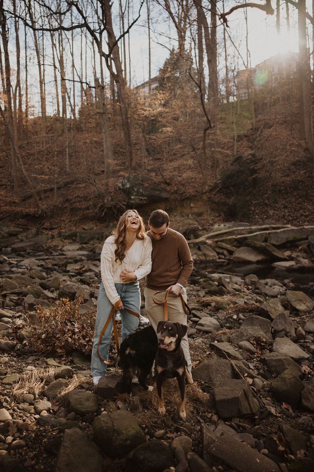 couple poses with dogs at winter engagement photoshoot