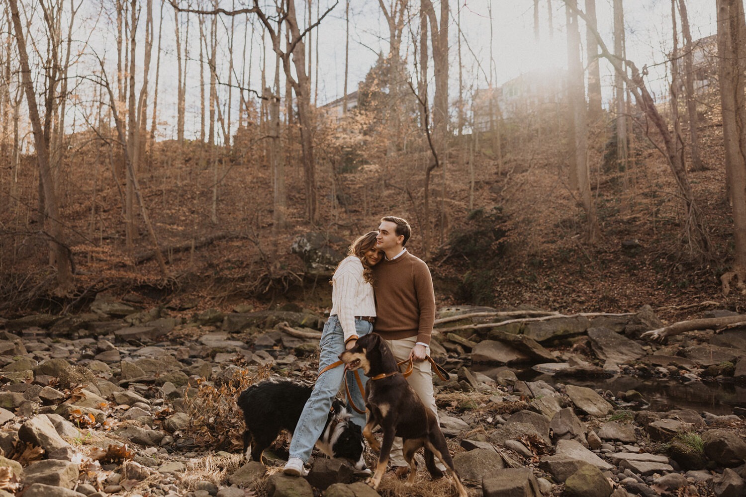 couple poses with dogs at winter engagement photoshoot