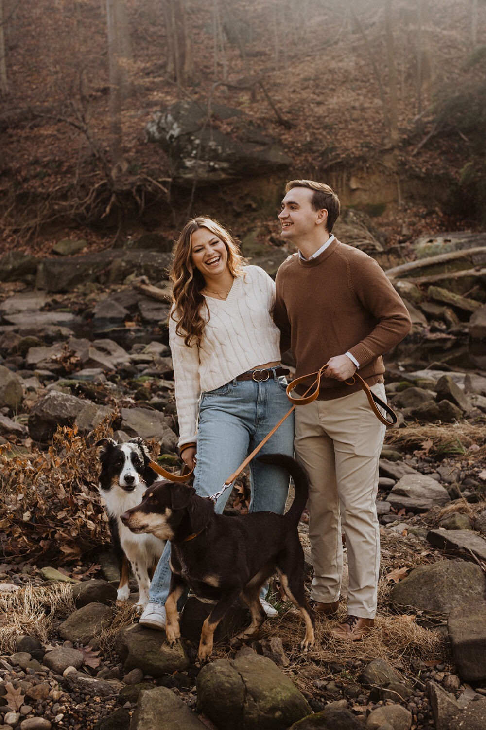 couple poses with dogs at winter engagement photoshoot