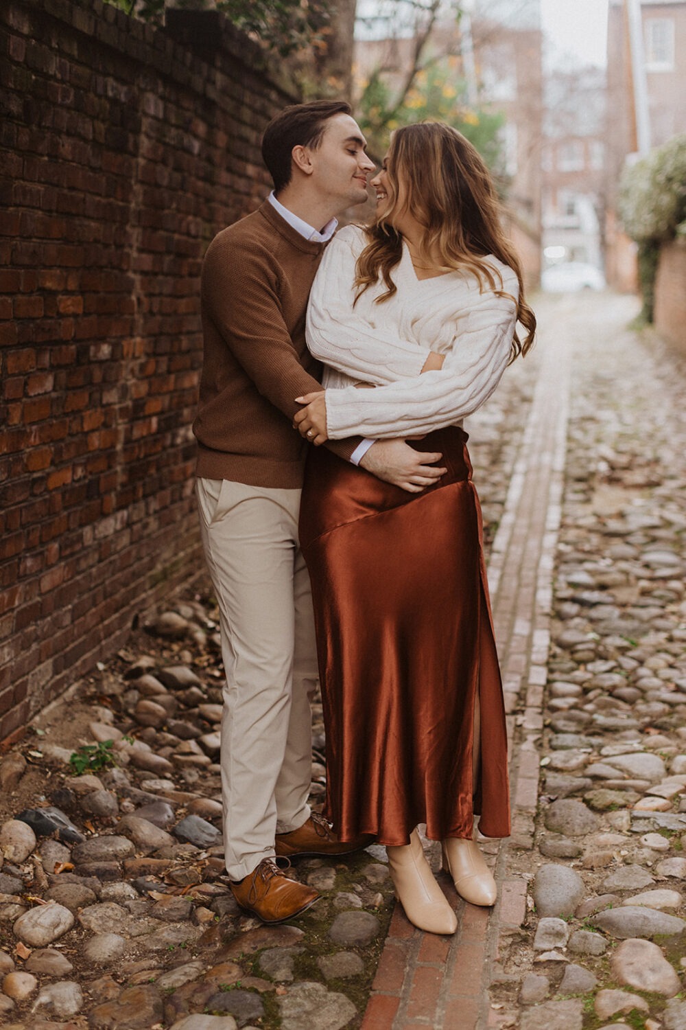 couple embraces on cobblestone streets at winter engagement photoshoot