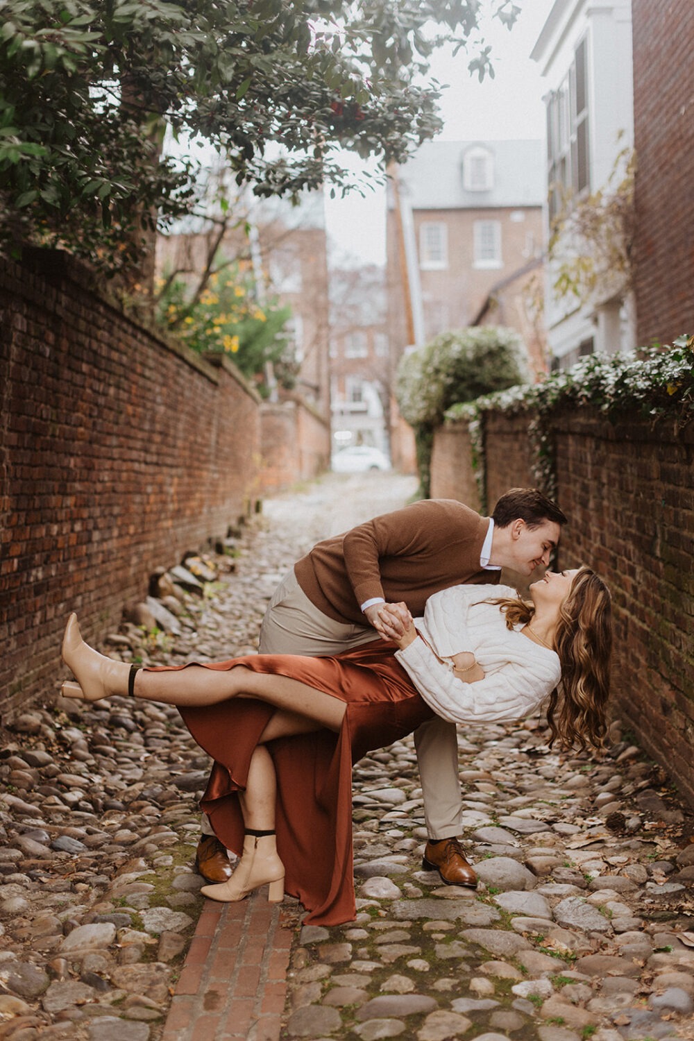 couple embraces on cobblestone streets at winter engagement photoshoot