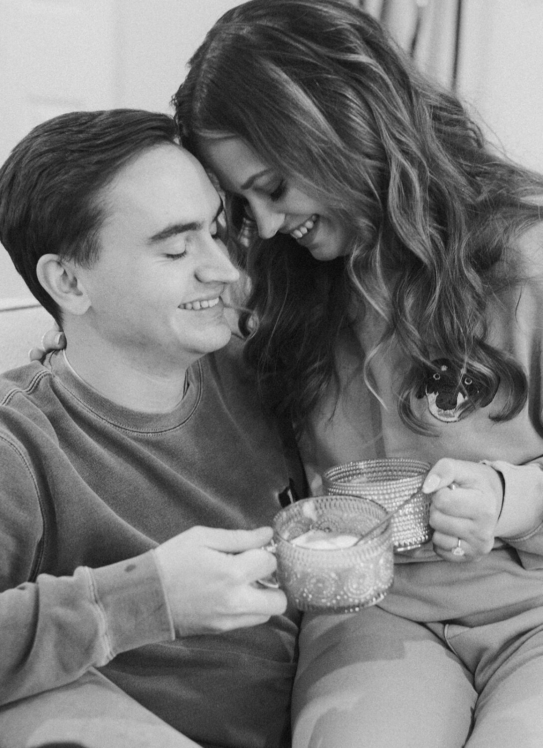 couple embraces while drinking coffee at winter engagement photoshoot