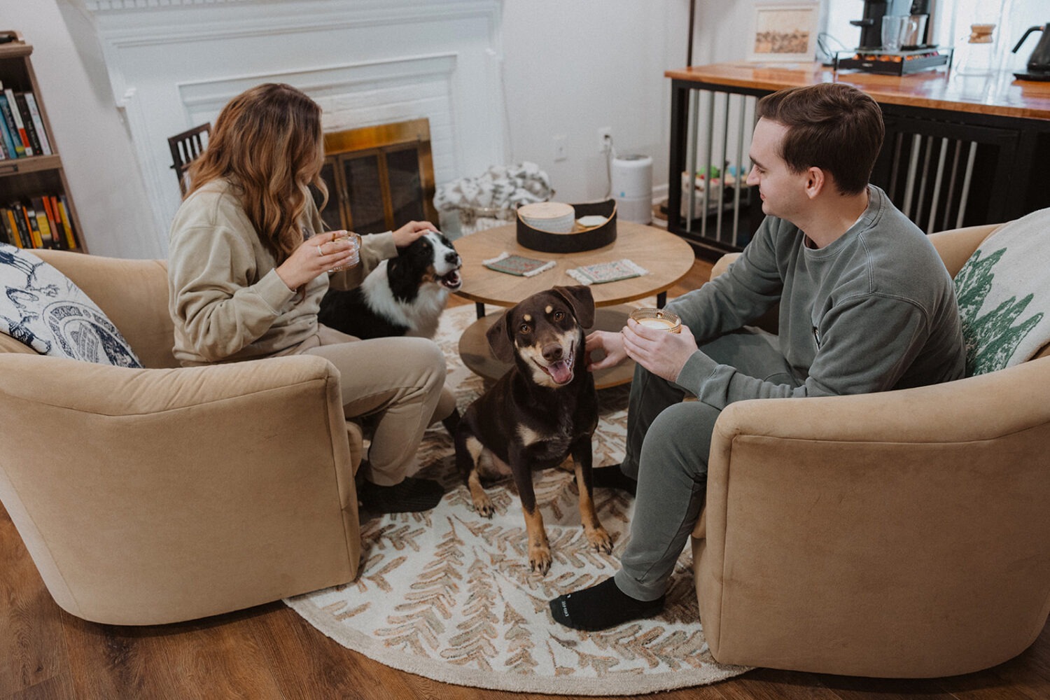 couple sits with dogs at home at winter engagement photoshoot