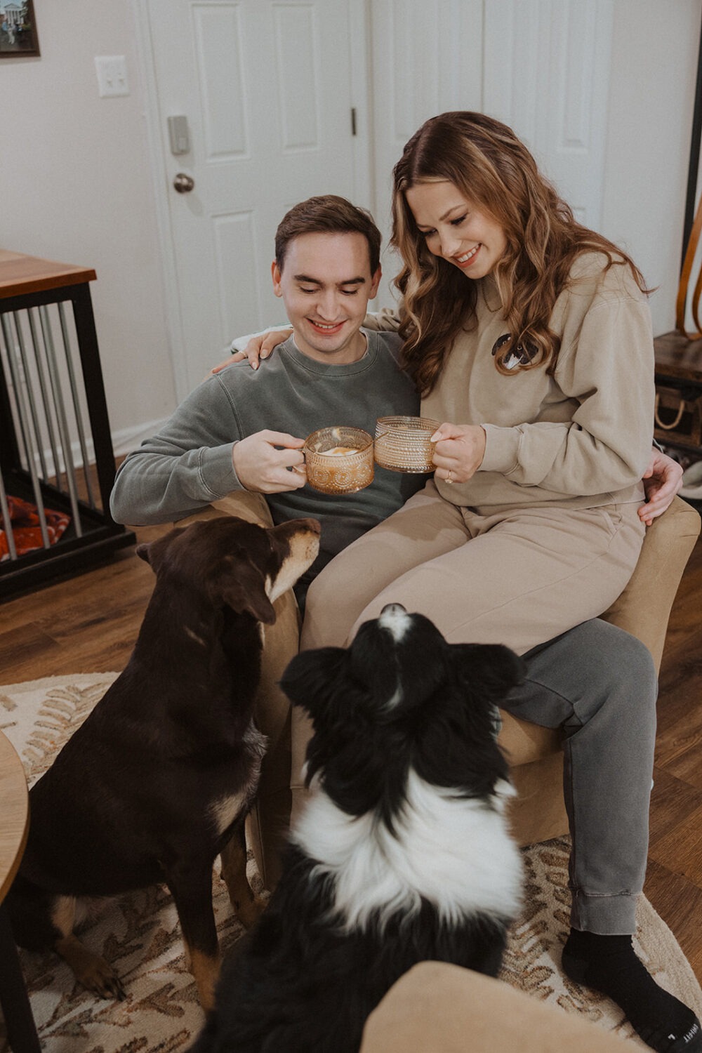 couple sits with dogs at home Christmas engagement session