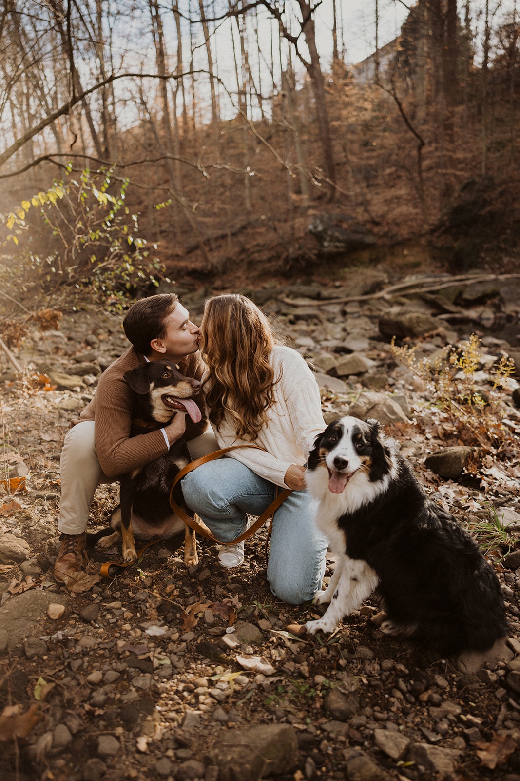 couple kisses during forest engagement session with pets