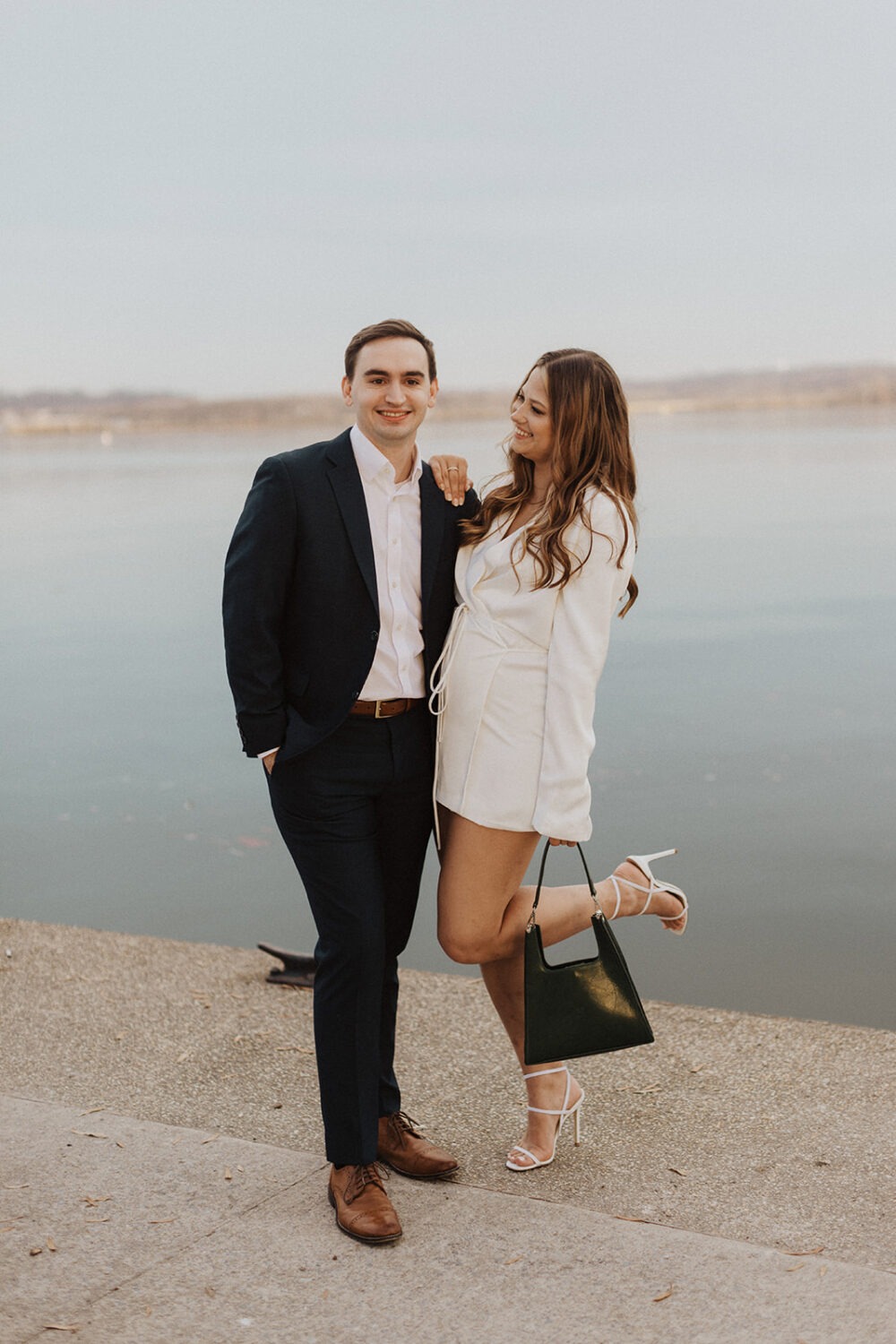 couple poses along waterfront at winter engagement photoshoot