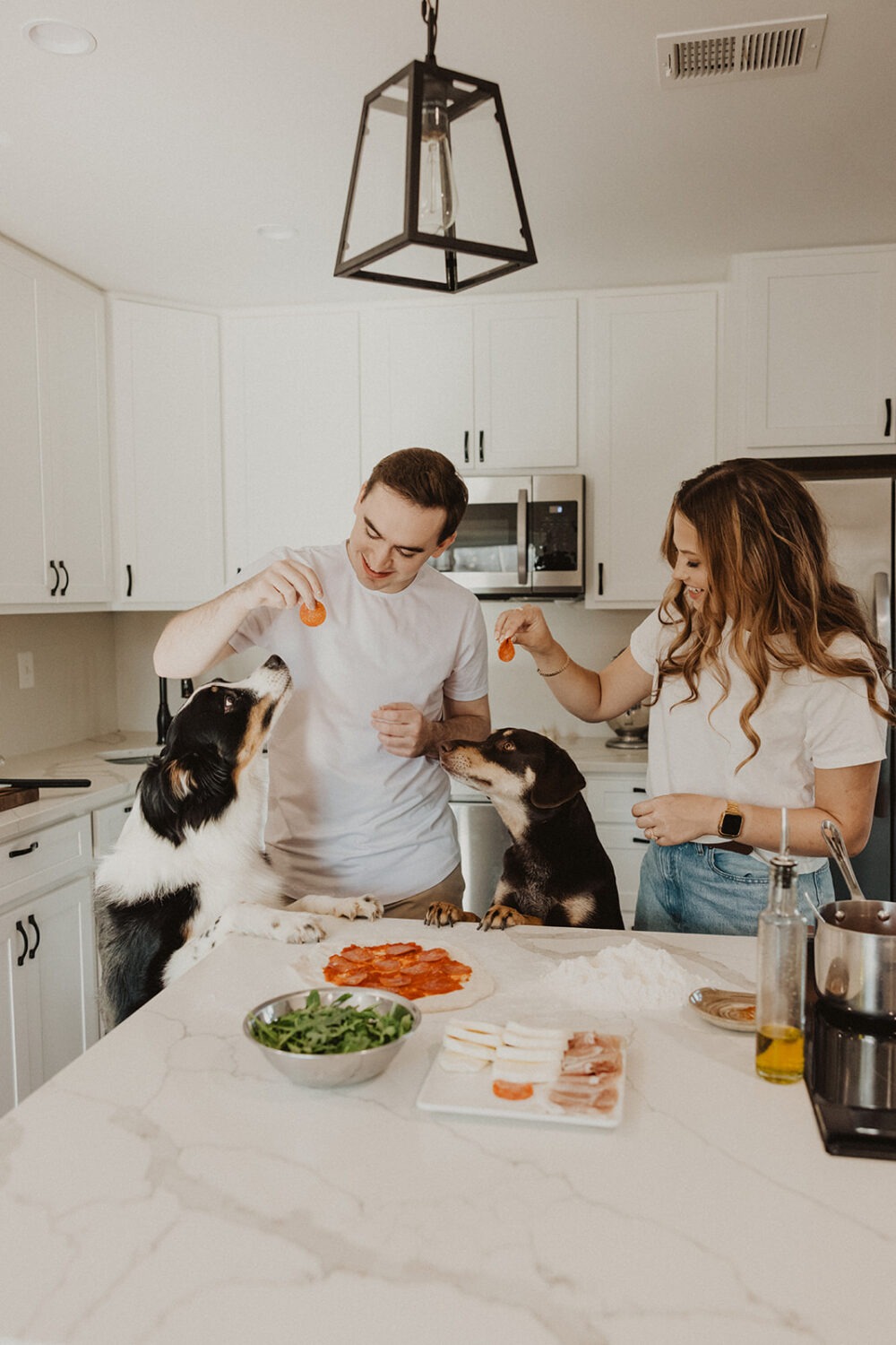 couple makes pizza with dogs at home engagement session