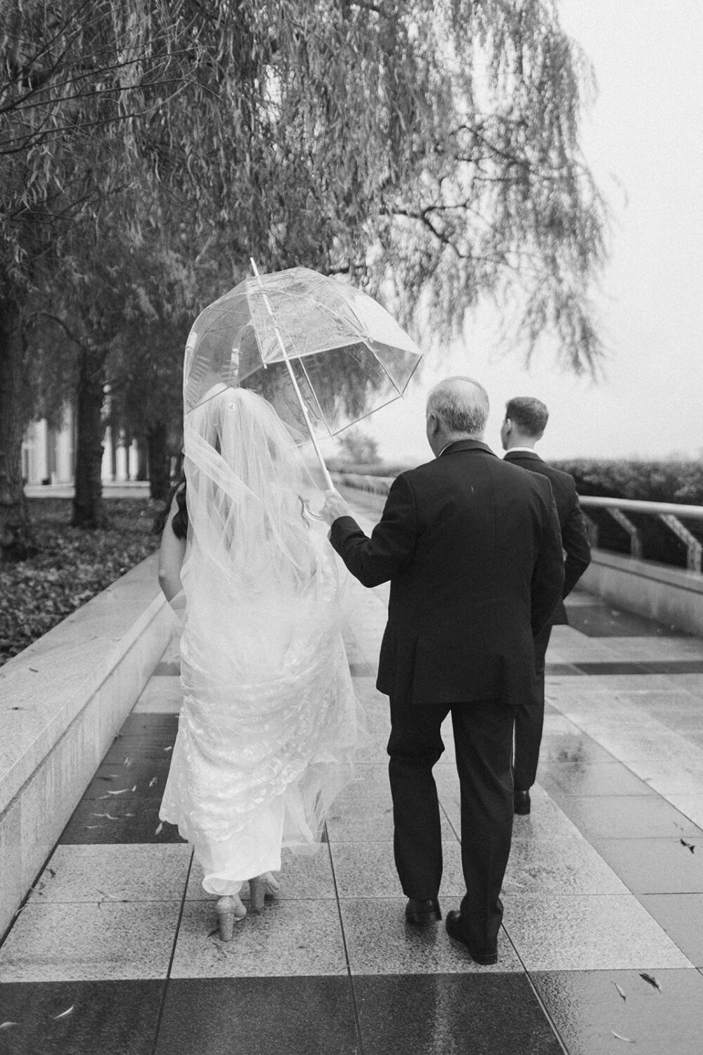 couple walks at rainy outdoor DC elopement