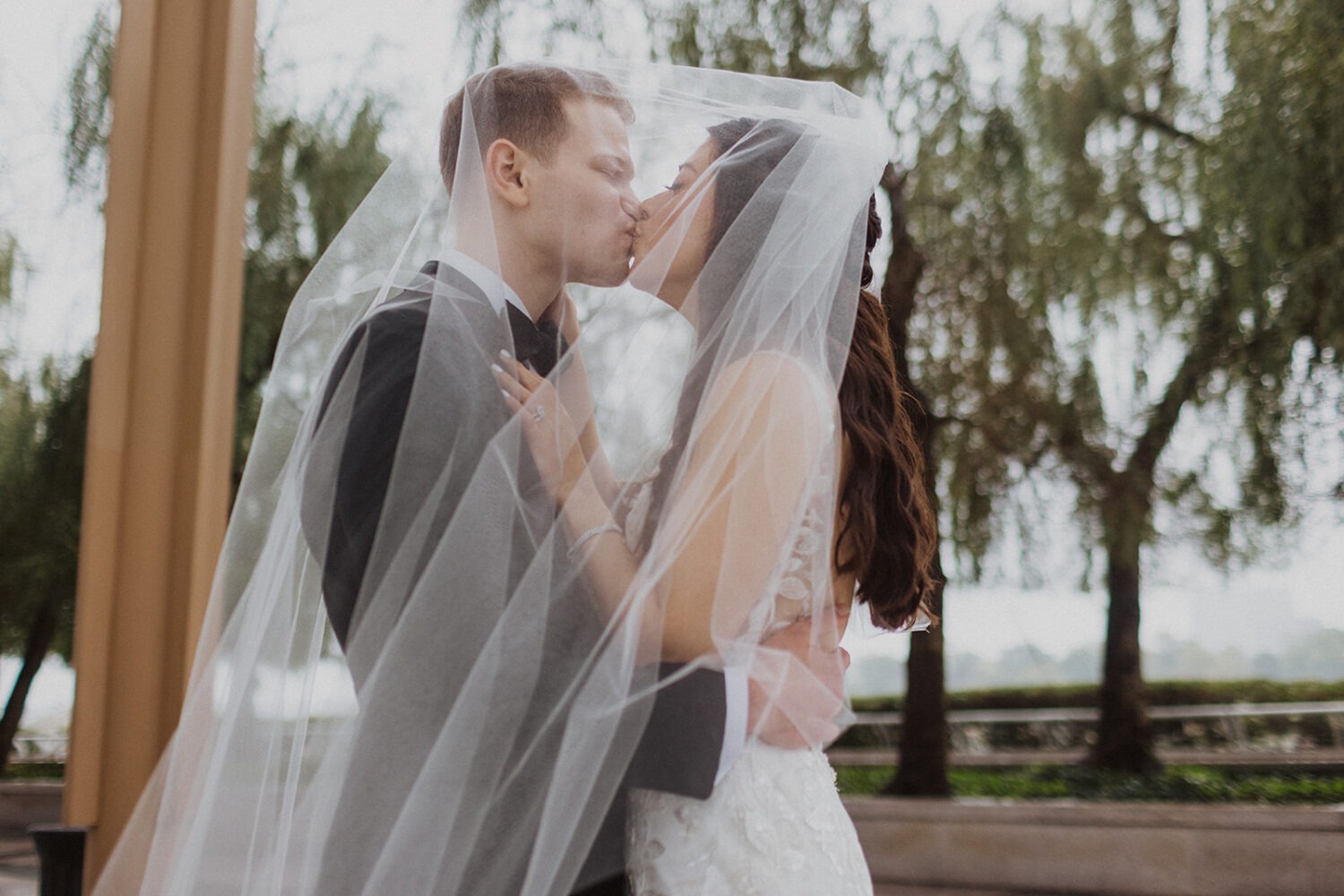 couple kisses under wedding veil