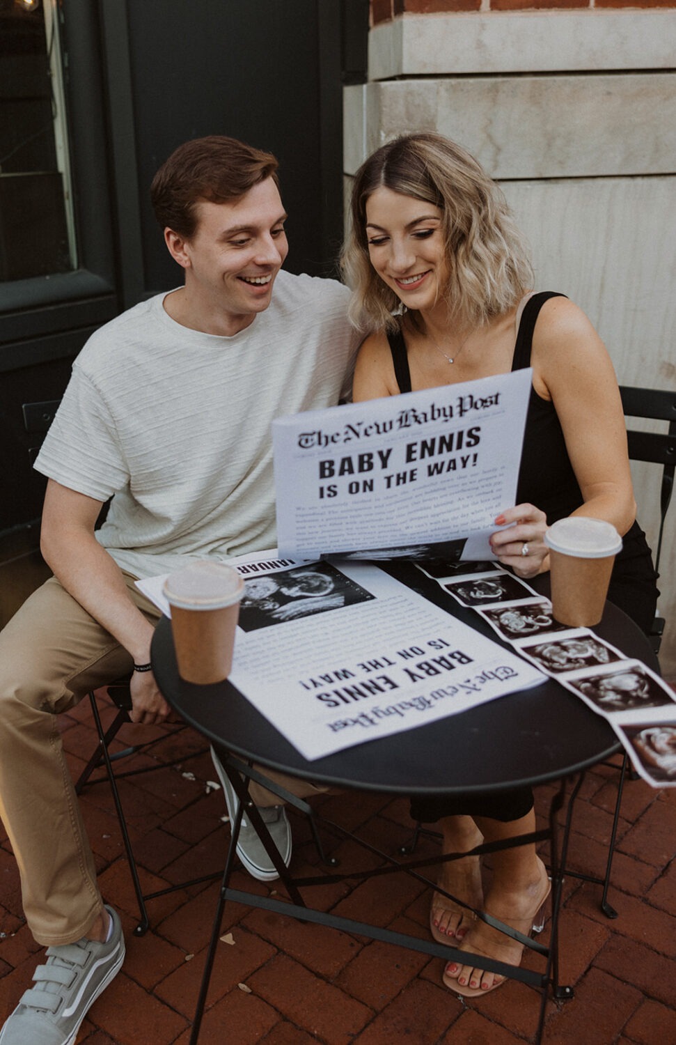 couple holds hands while enjoying coffee and their baby sonogram