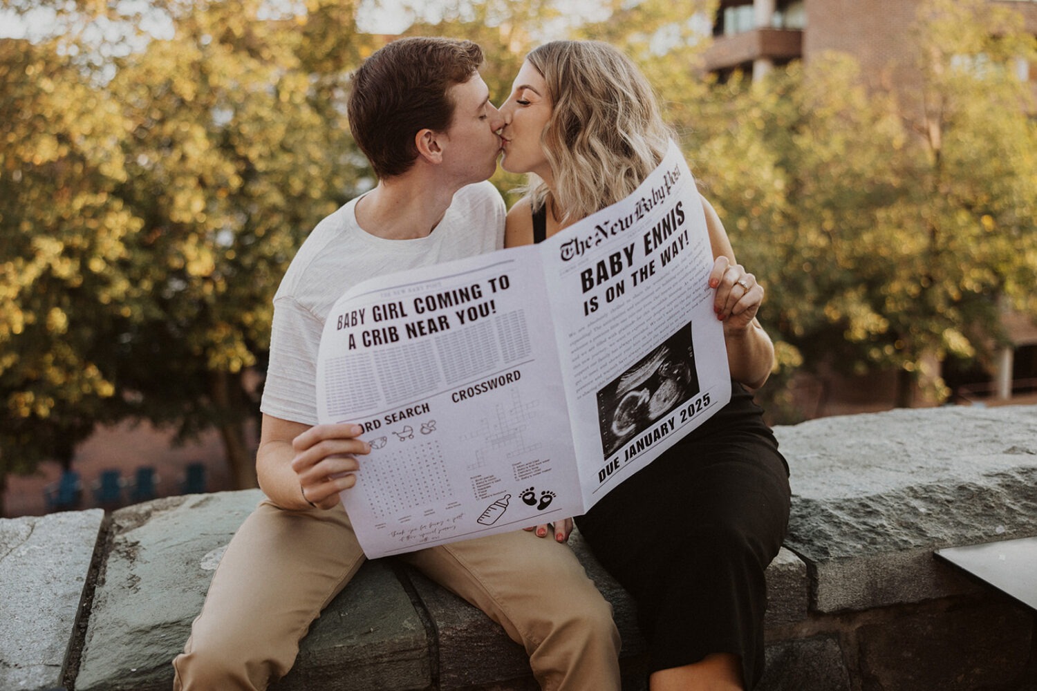 couple kisses with baby announcement newspaper 