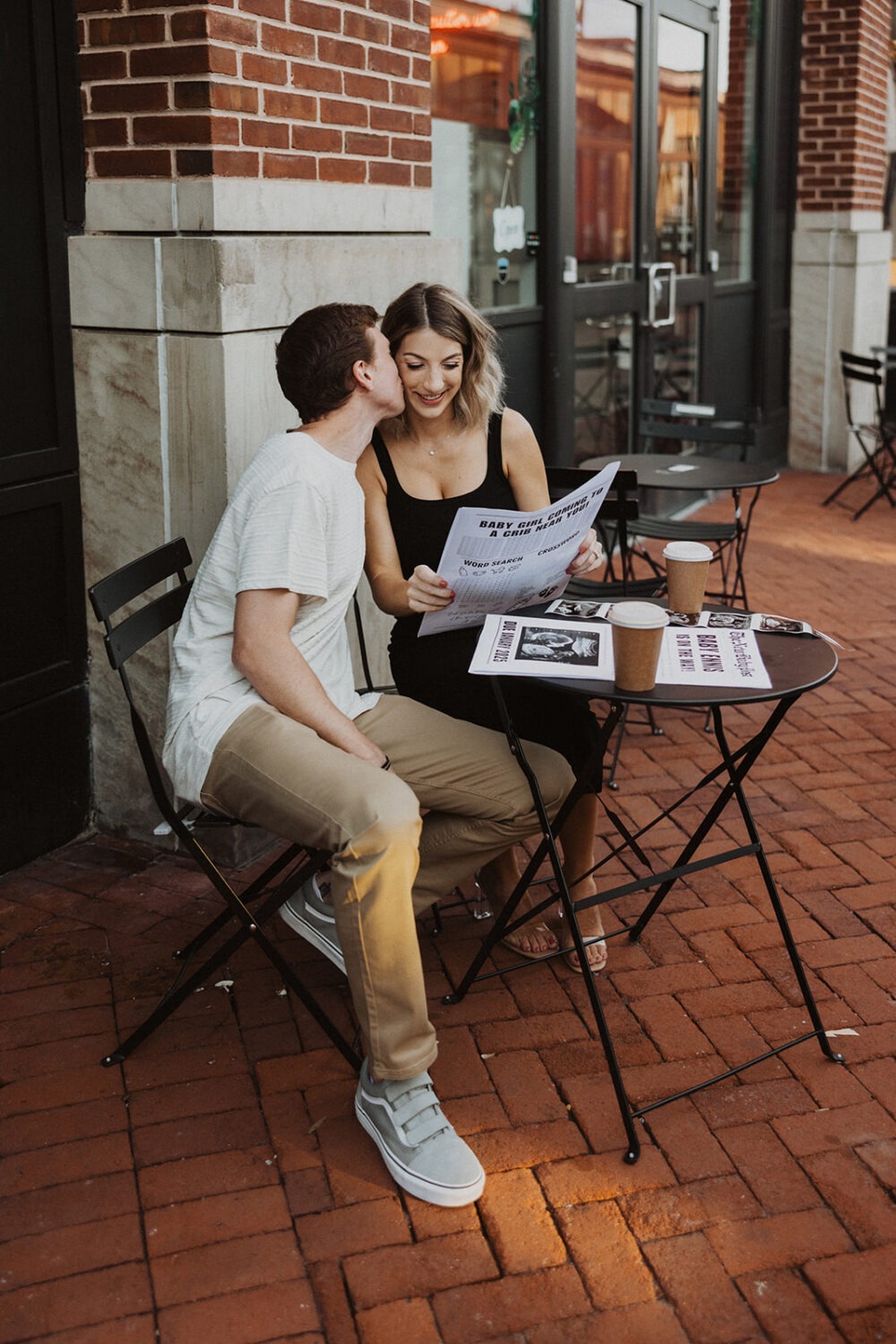 couple holds hands while enjoying coffee and their baby sonogram