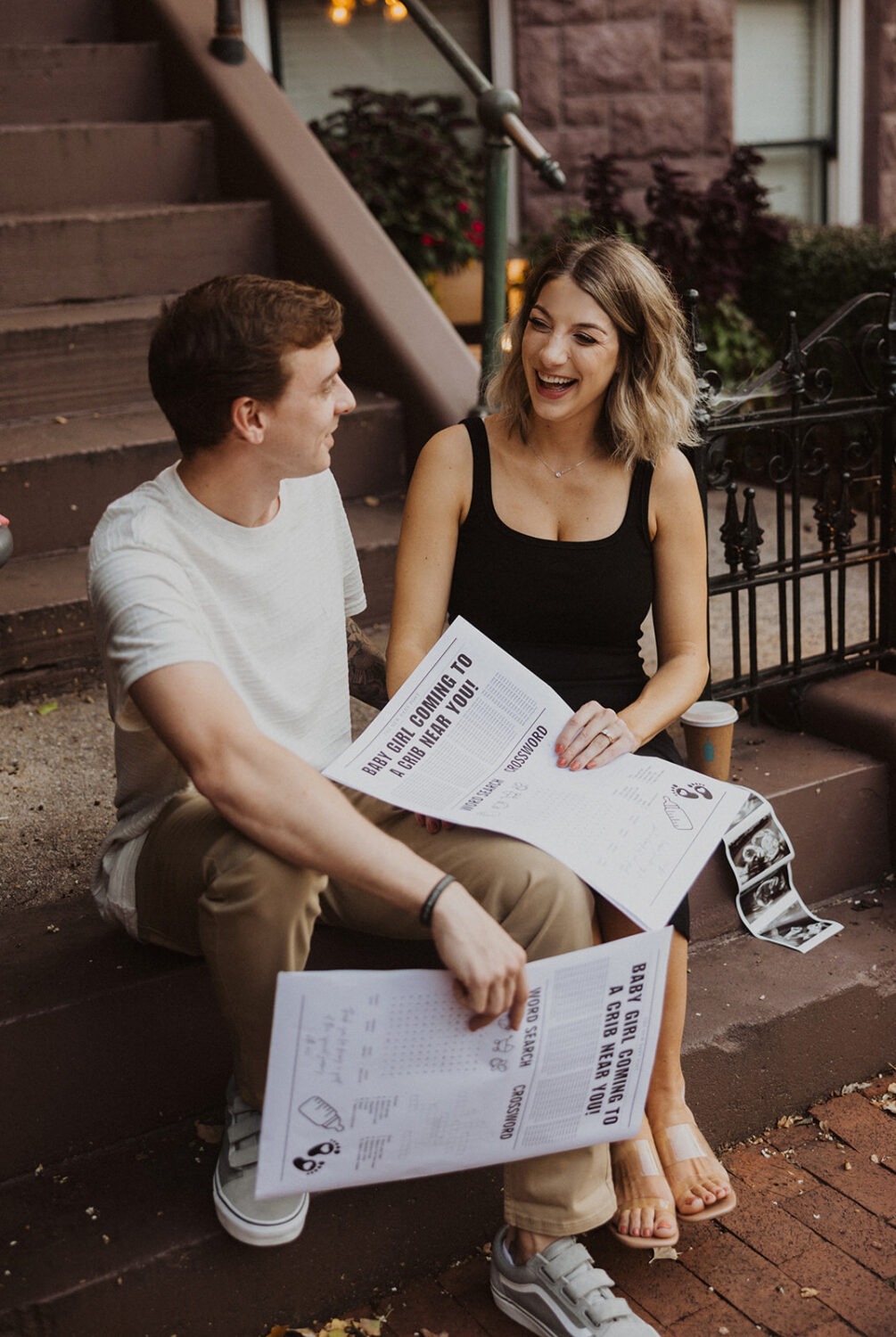 couple poses with their baby announcement newspaper while taking couples maternity photos