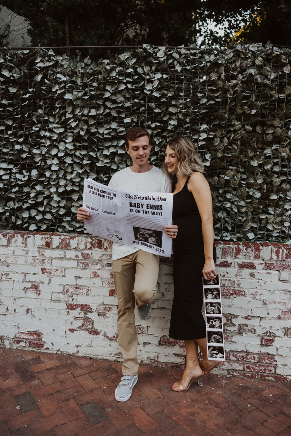 Couple reads their baby announcement while taking couples maternity photos 