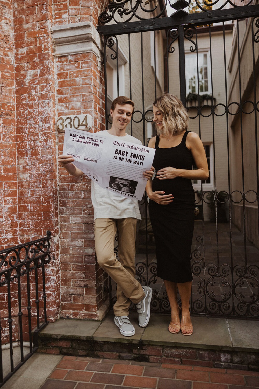 couple poses with their baby announcement newspaper while taking couples maternity photos