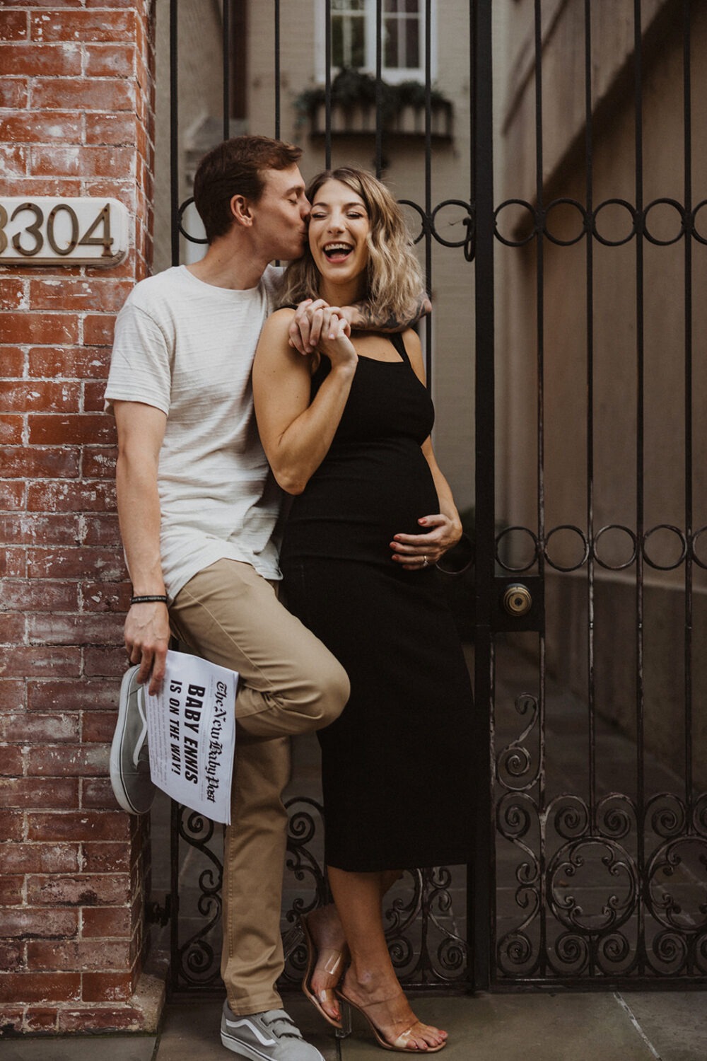 couple poses with their baby announcement newspaper while taking couples maternity photos