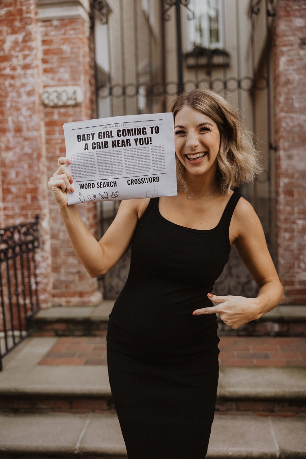 Woman holds up baby announcement newspaper