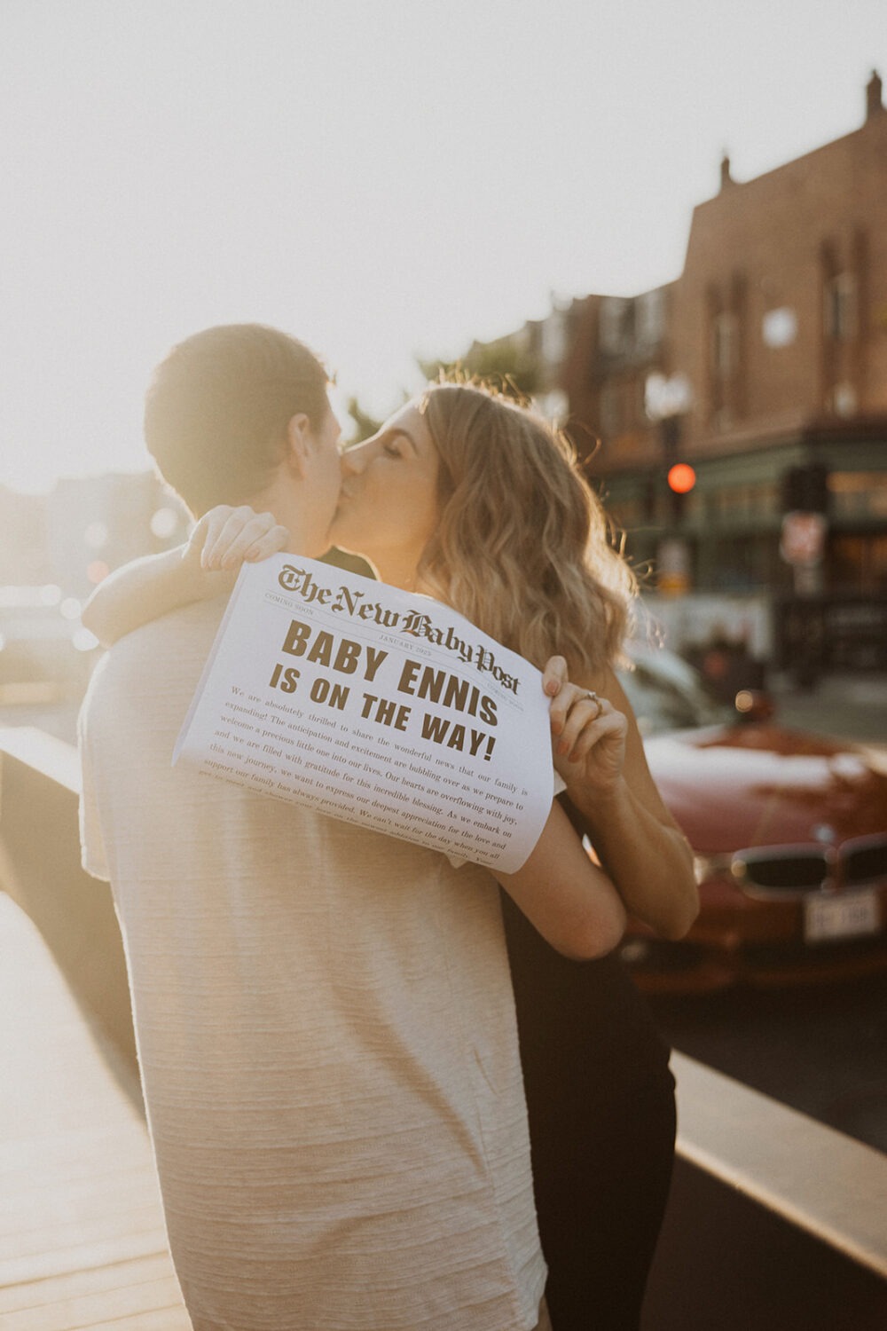 couple kisses with baby announcement newspaper 