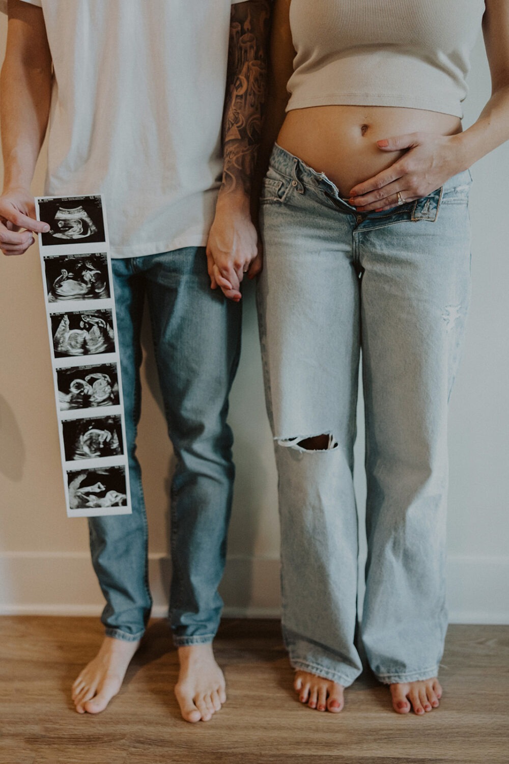 couple embraces while holding sonogram