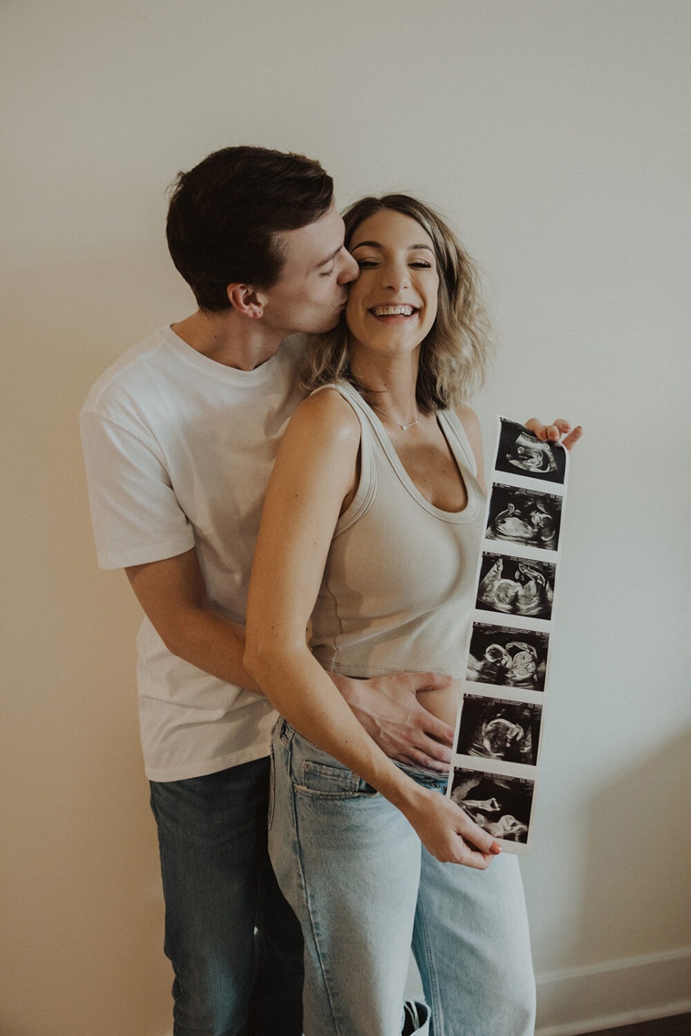 couple embraces while holding sonogram