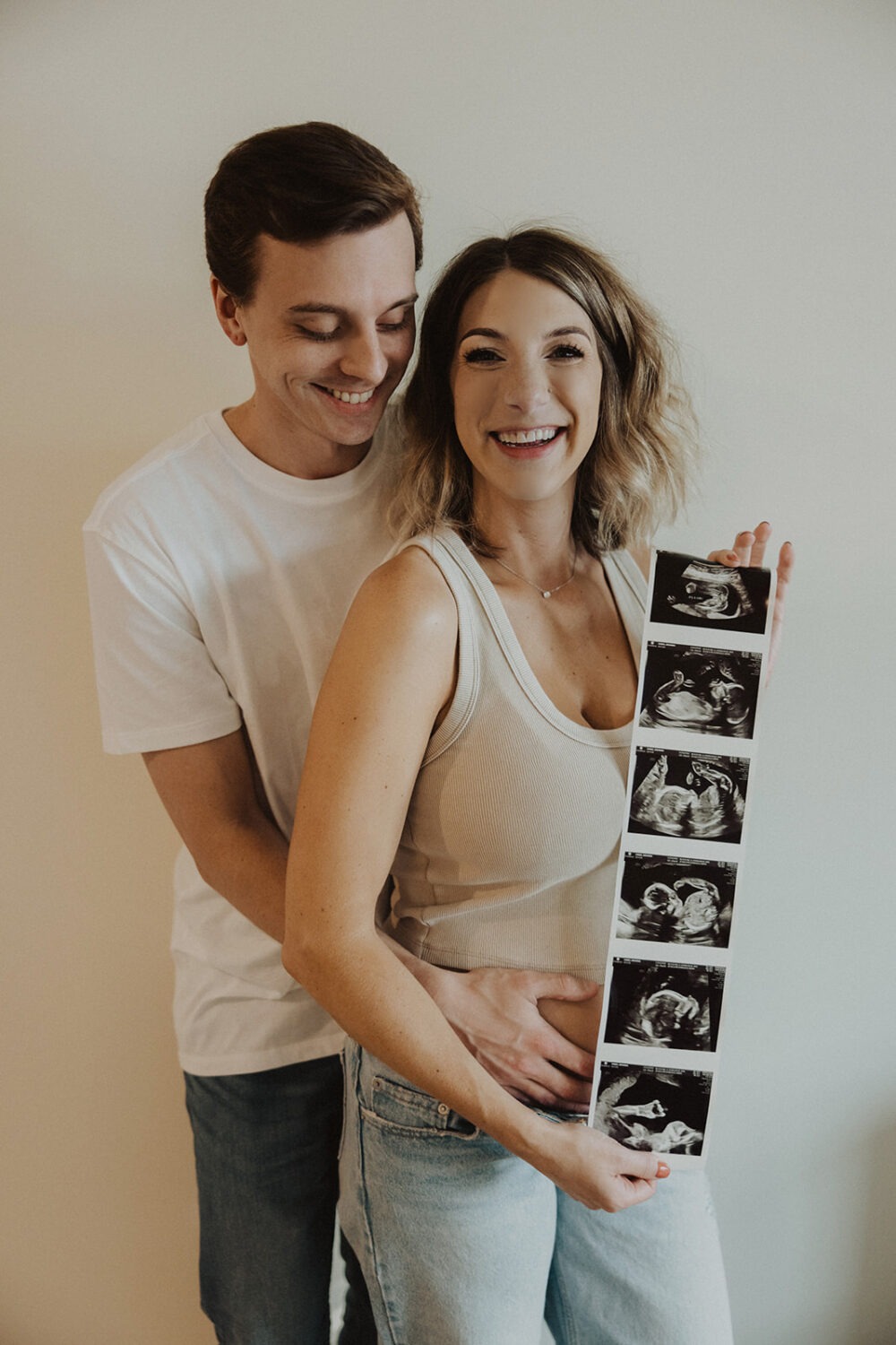 couple embraces while holding sonogram