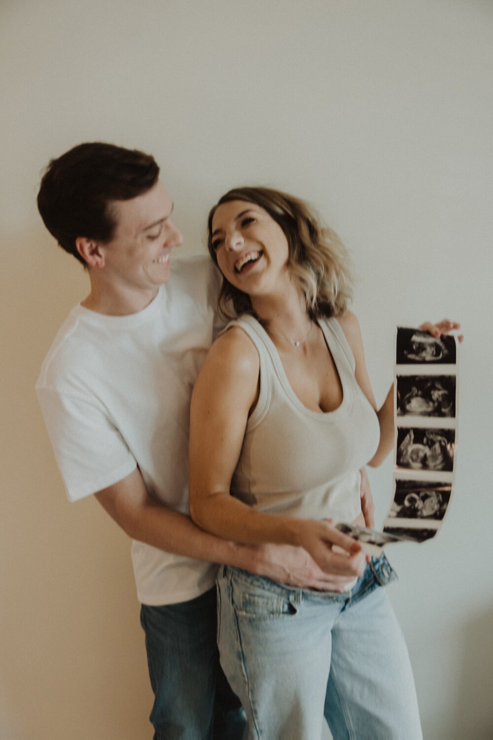 couple embraces while holding sonogram