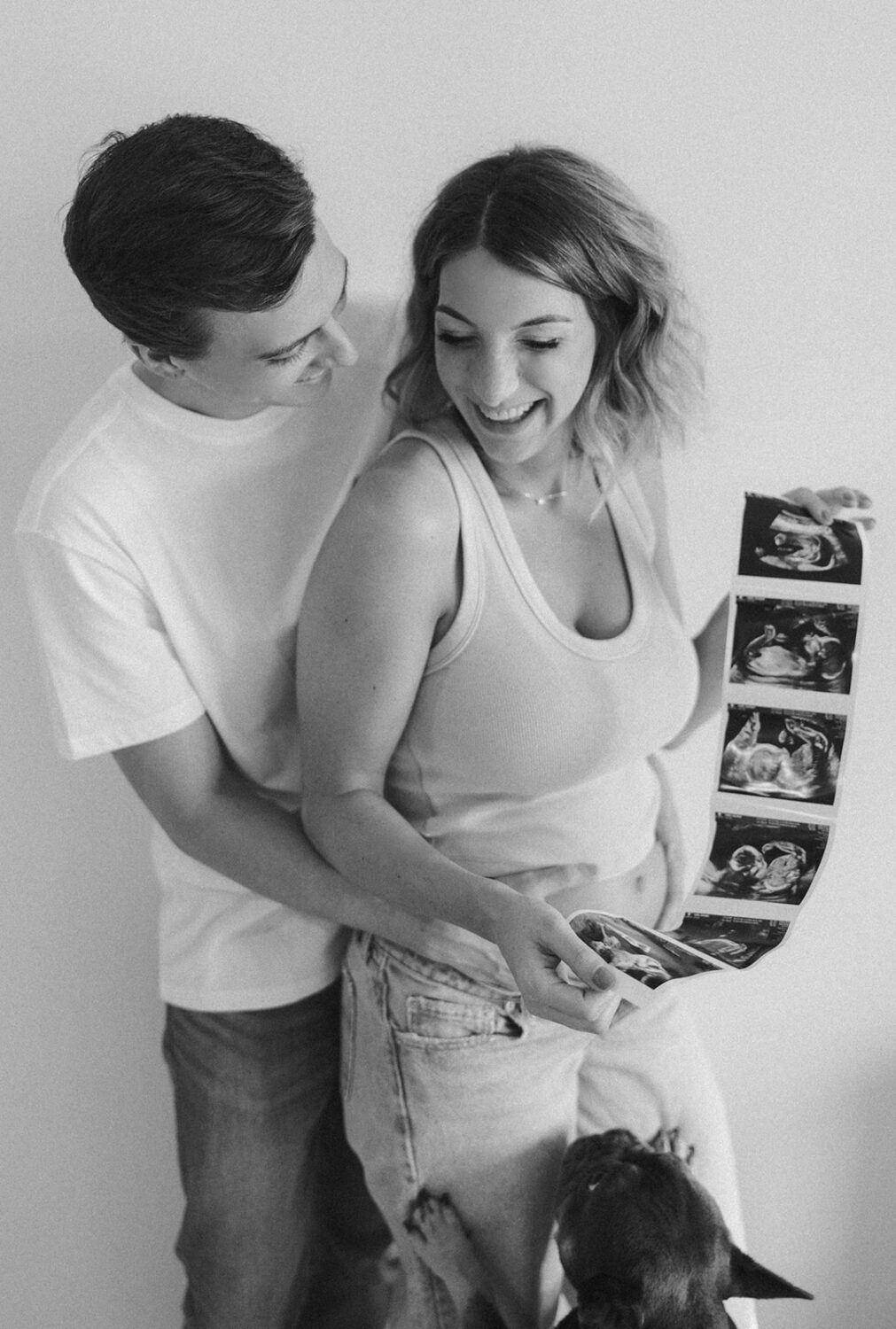 couple embraces while holding sonogram