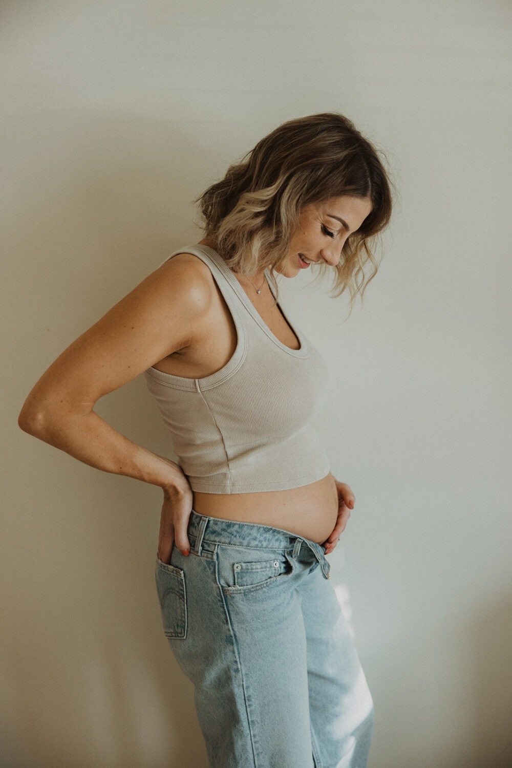 Woman poses in her home for couples maternity photos