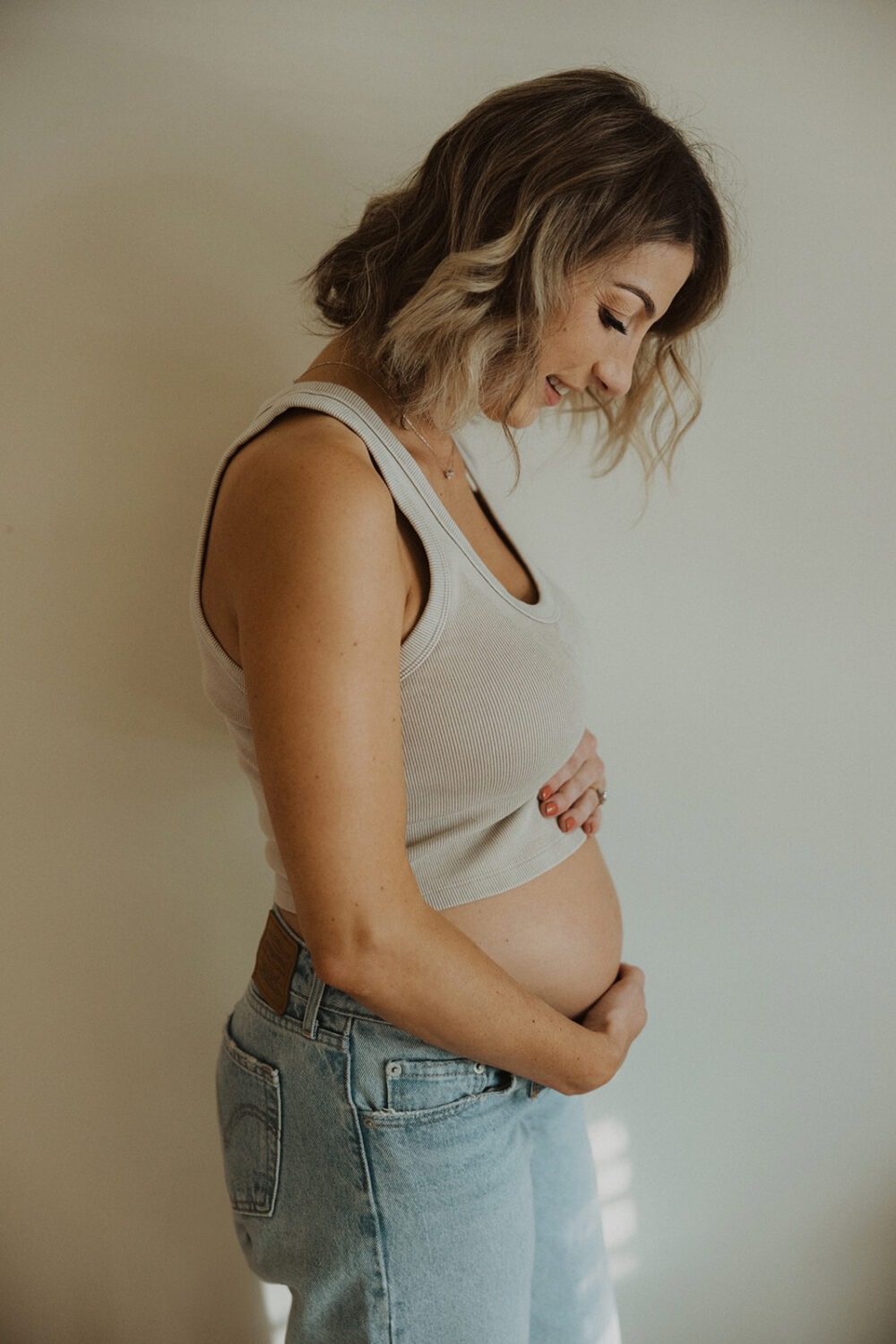 Woman poses in her home for couples maternity photos