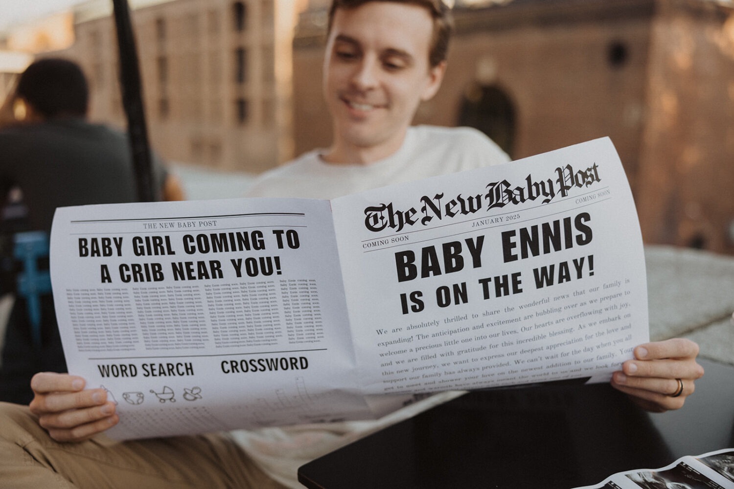 Husband holds up baby announcement newspaper