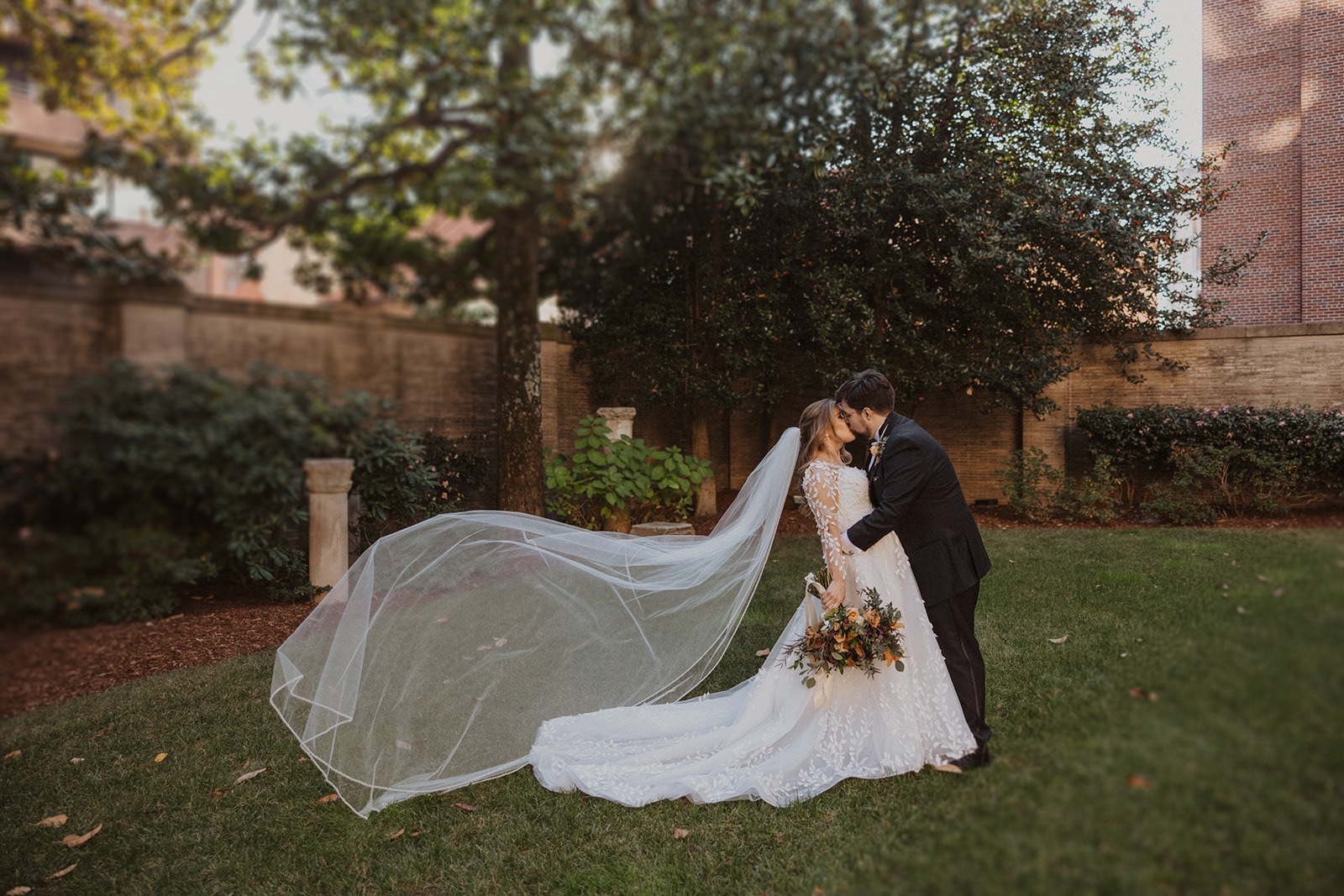 couple kisses with veil flowing in wind