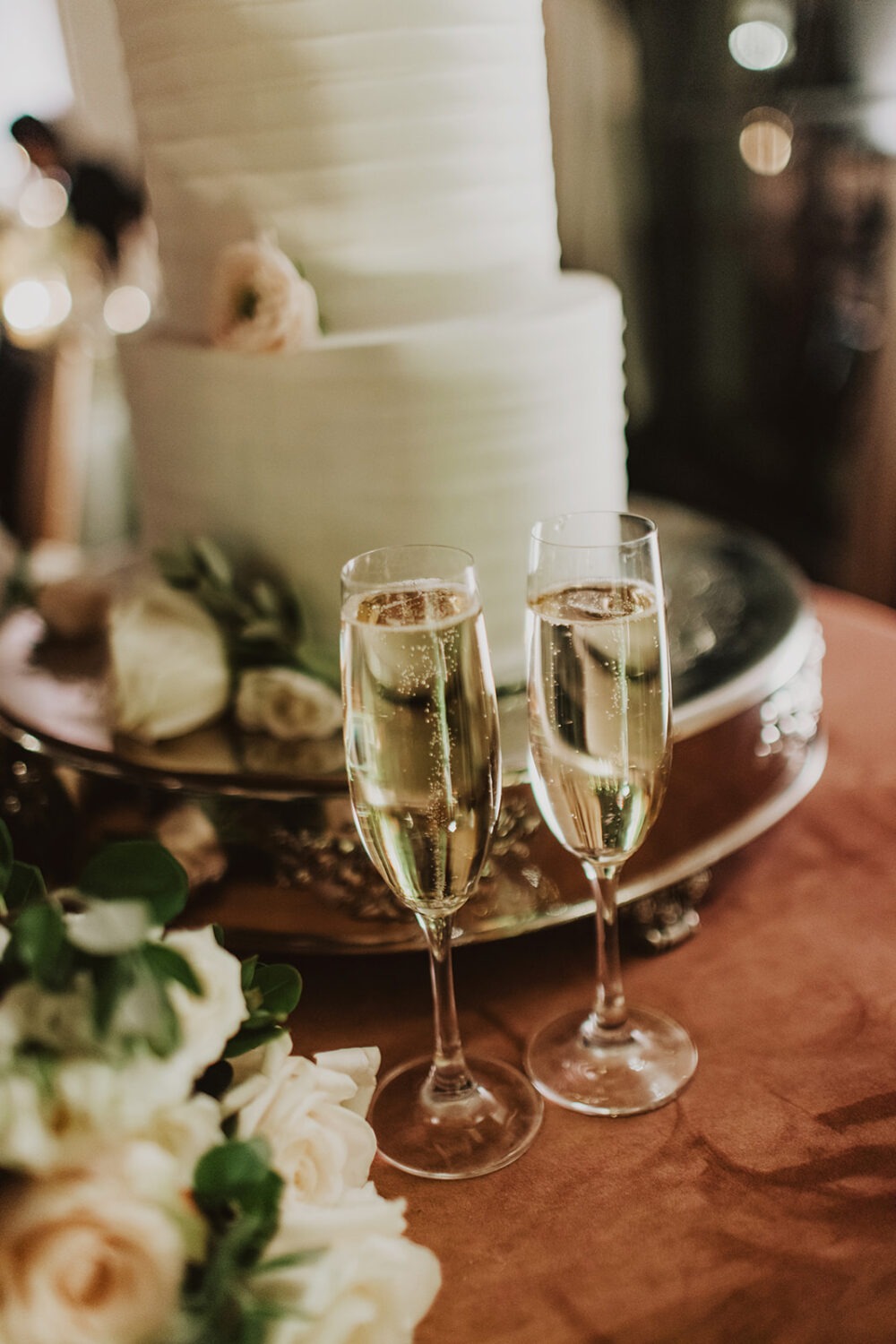 filled champagne glasses beside white wedding cake