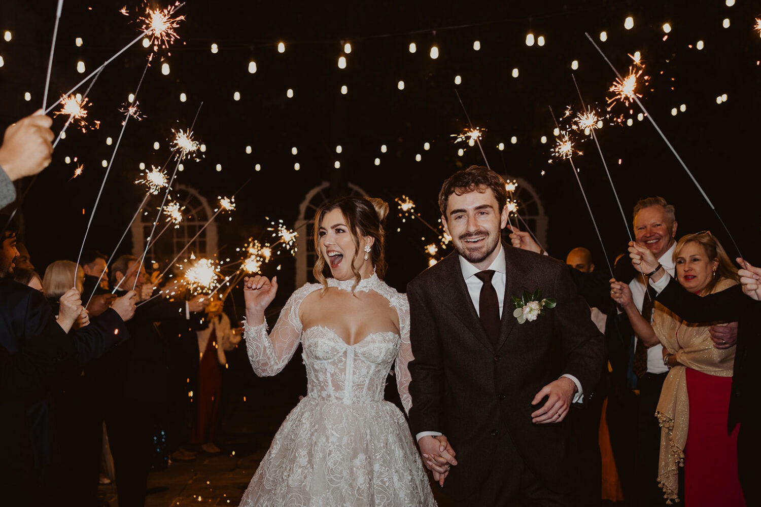 couple walks under sparkler exit
