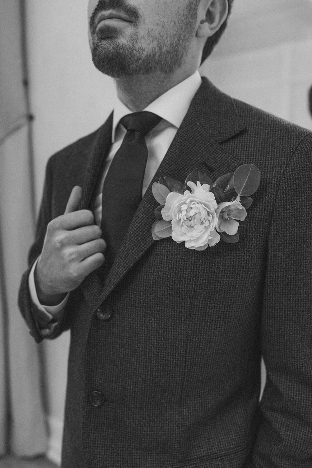 groom poses wearing flower boutonniere