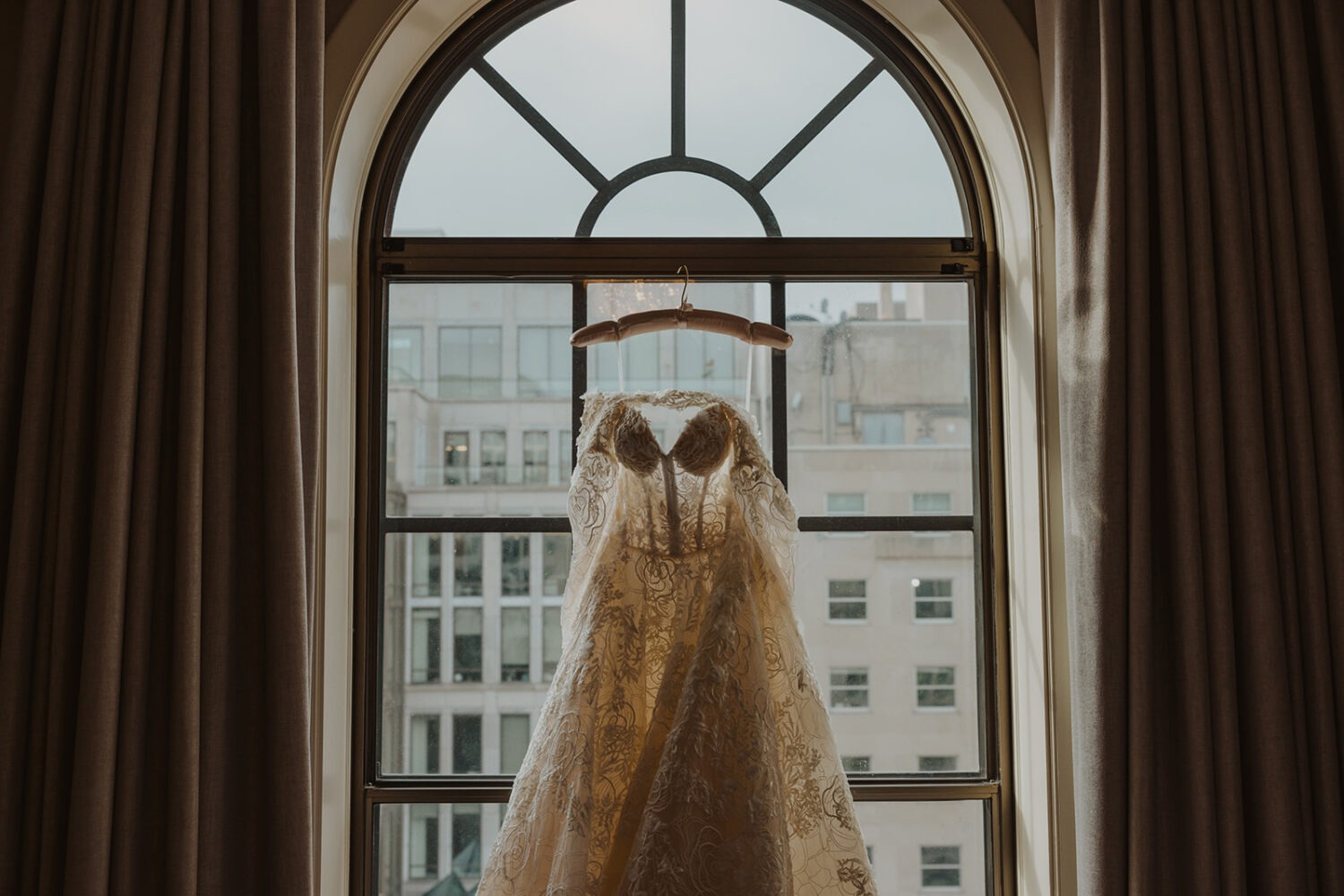 white wedding dress hangs over window