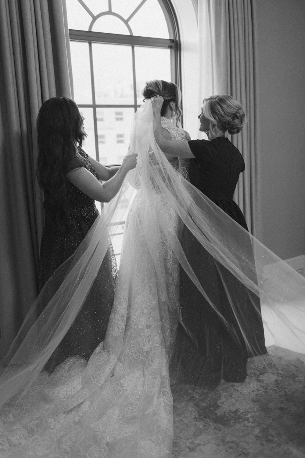 bridesmaids put wedding veil on bride
