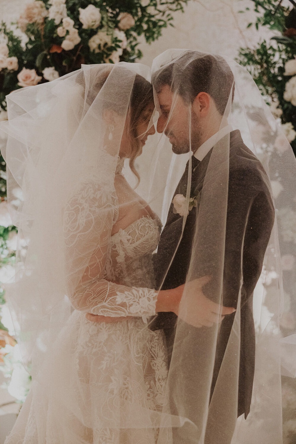 couple embraces under wedding veil
