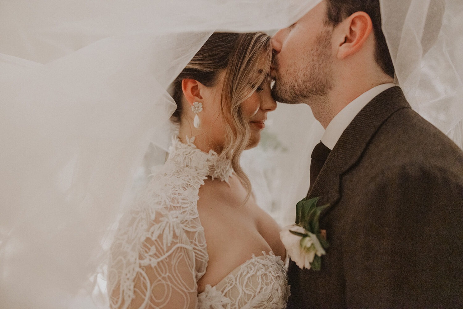 couple kisses under wedding veil