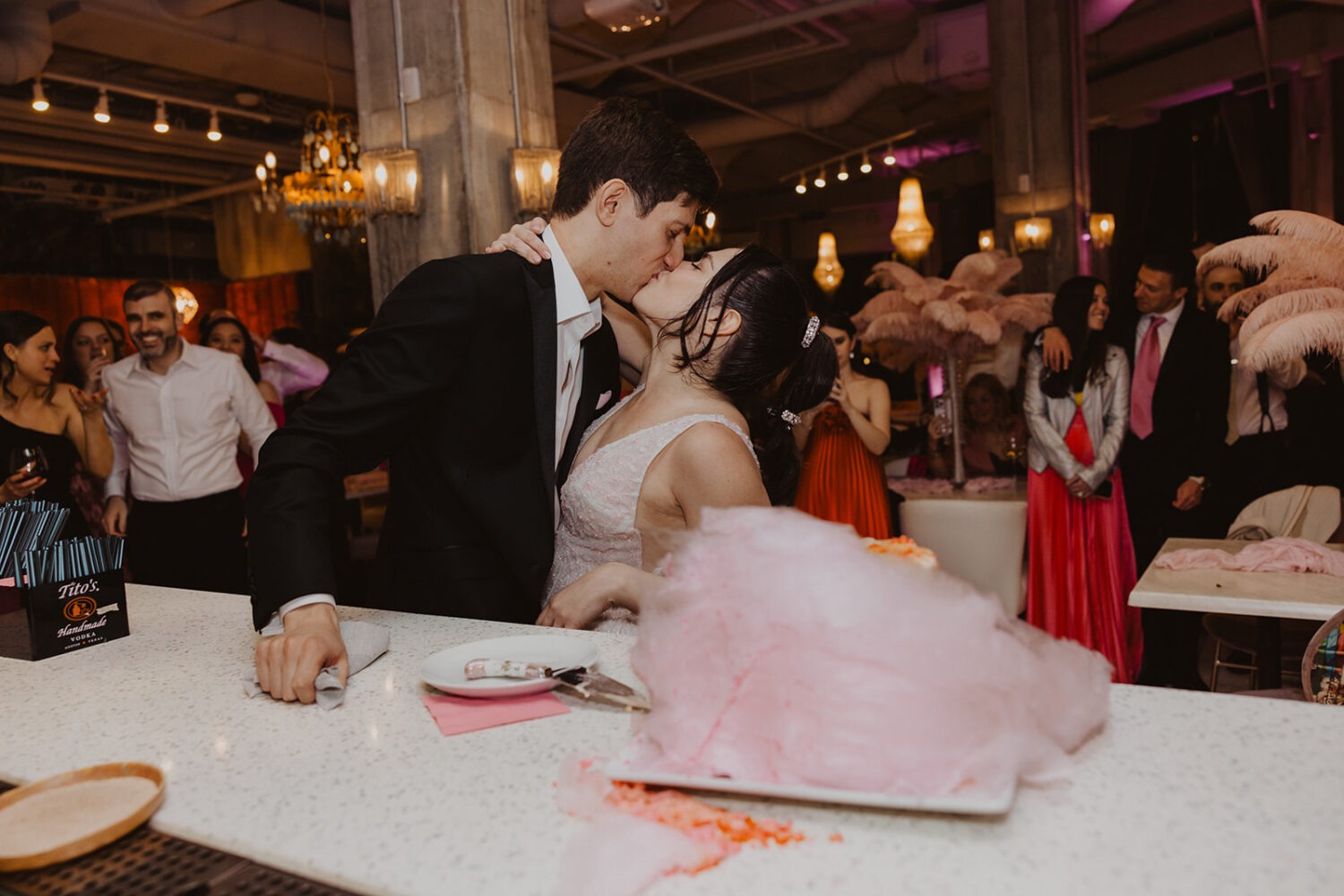 couple kissing after cutting pink cotton candy wedding cake