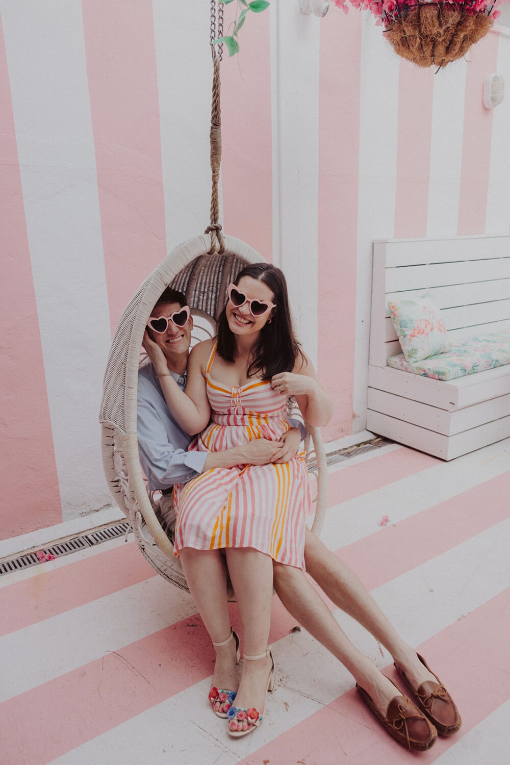 couple sitting in hanging chair during engagement shoot 