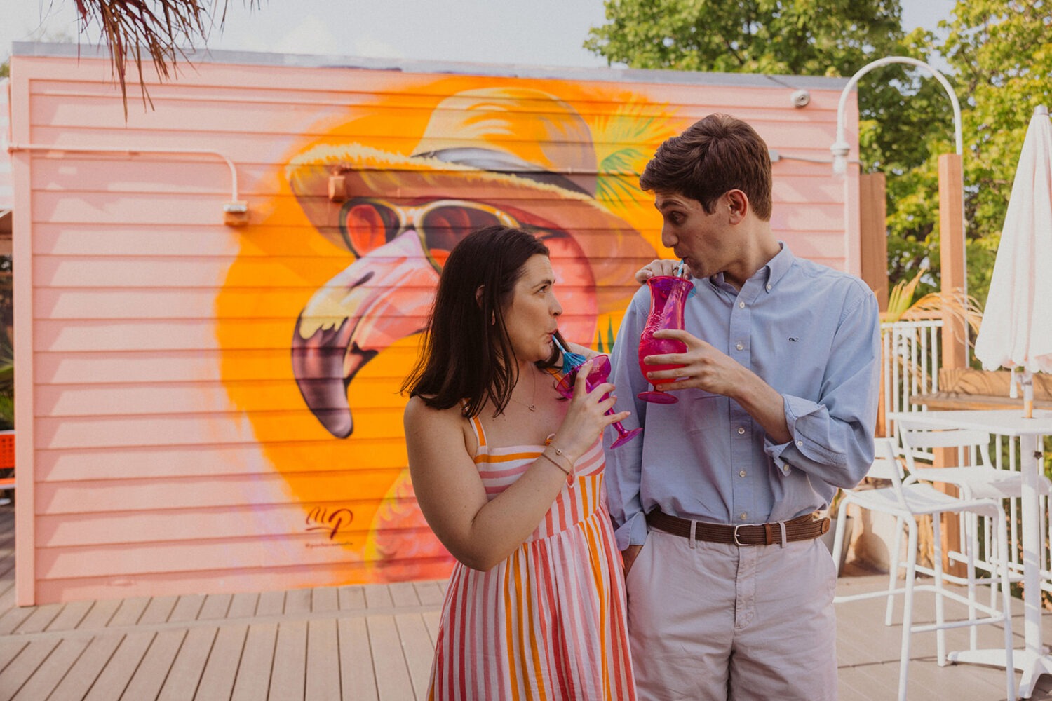 couple poses with tropical drinks  during engagement shoot