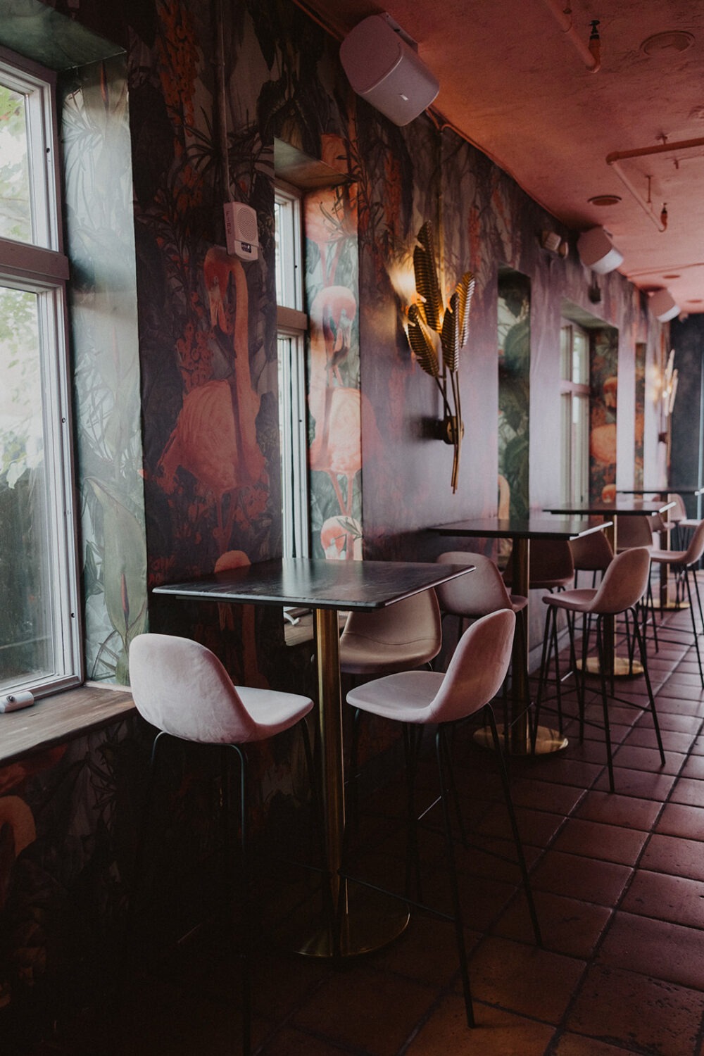 pink themed room with tropical wallpaper and soft pink chairs