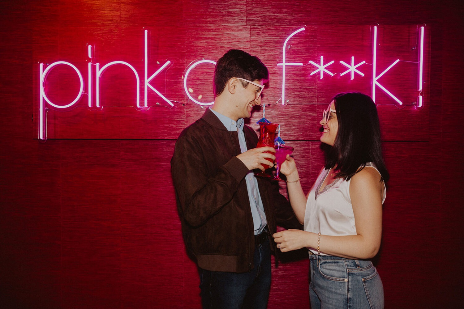 couple poses with tropical drinks  during engagement shoot