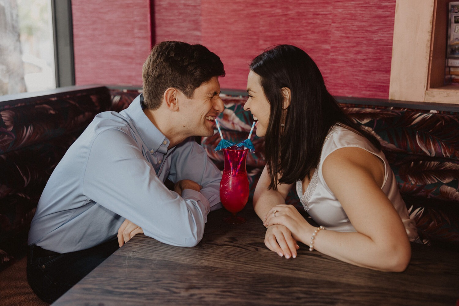 couple shares tropical drink during engagement shoot