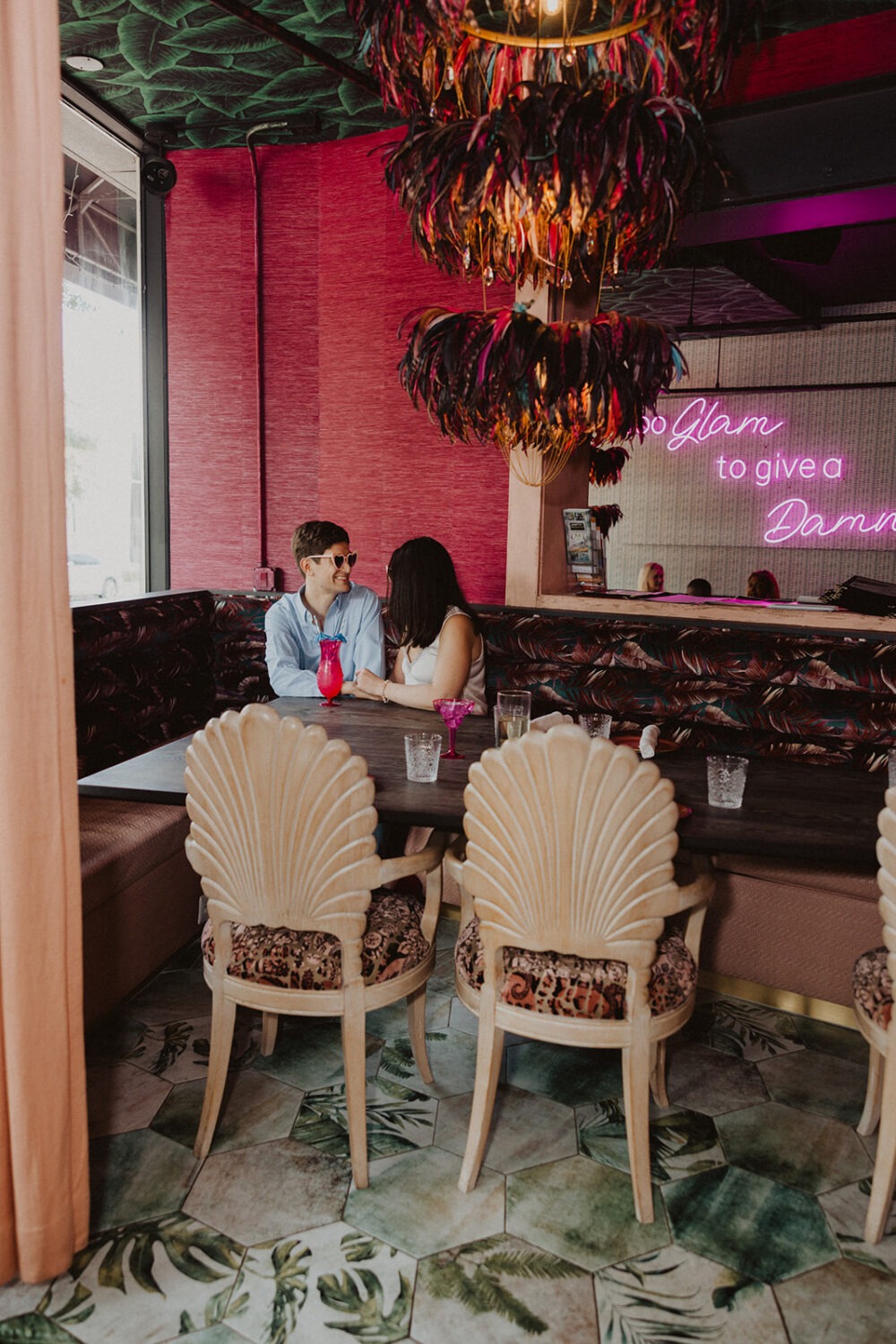 couple sitting in tropical-themed lounge during engagement shoot 