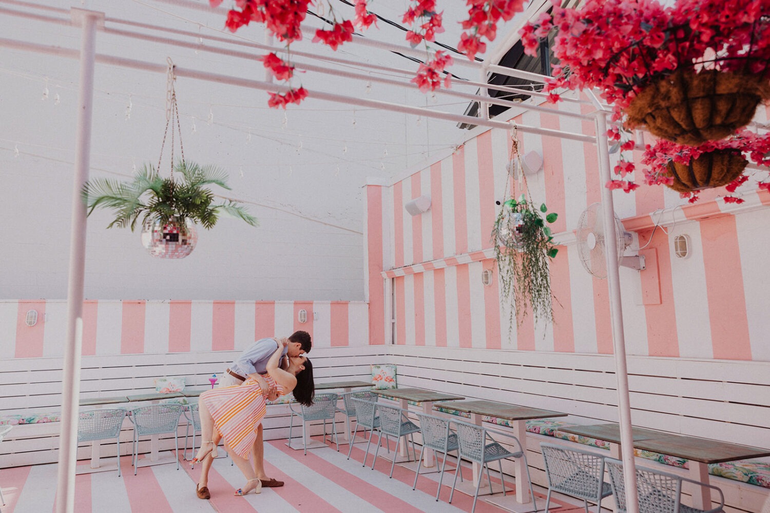 couple kisses in pink and white striped room during engagement shoot