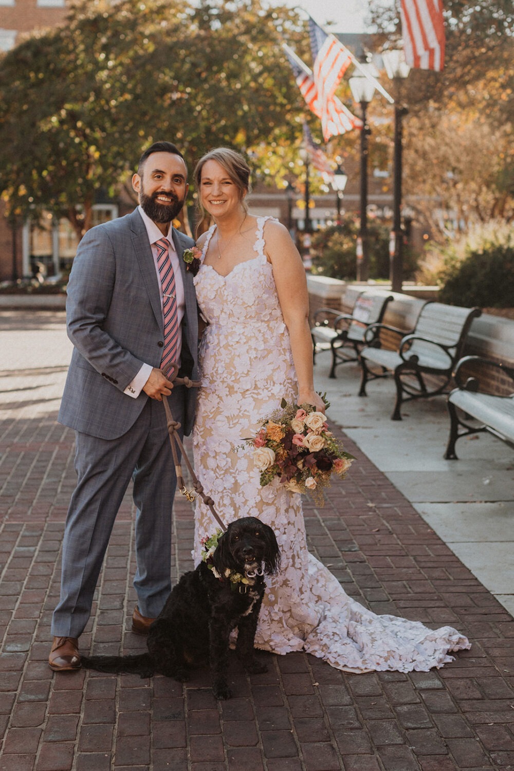 couple poses with their dog on their wedding day