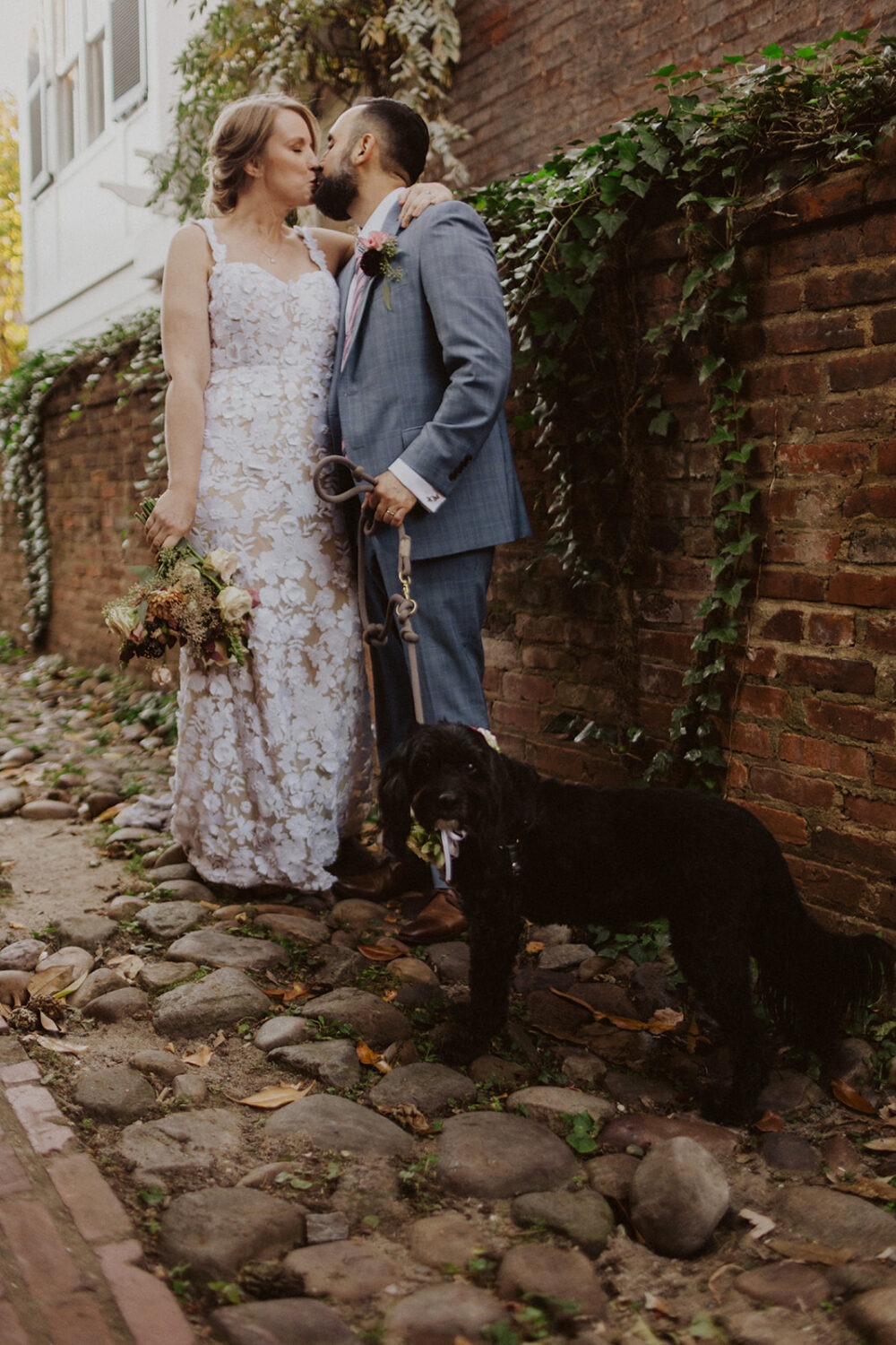 couple kissing with their dog on their wedding day