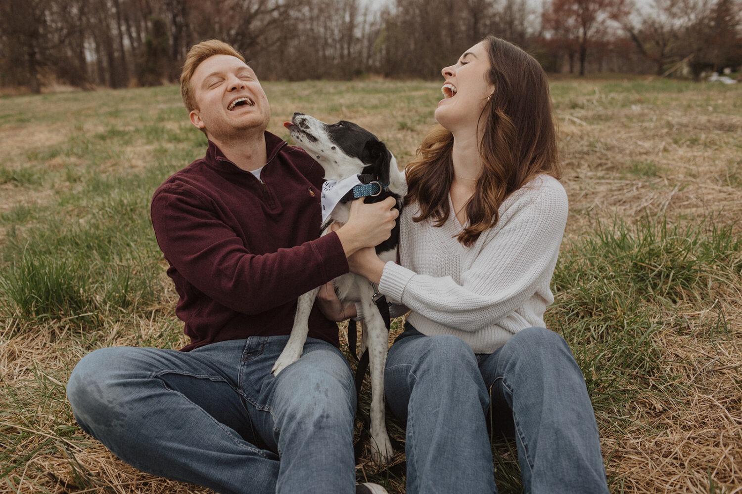 couple laughing as their dog tries licking their face